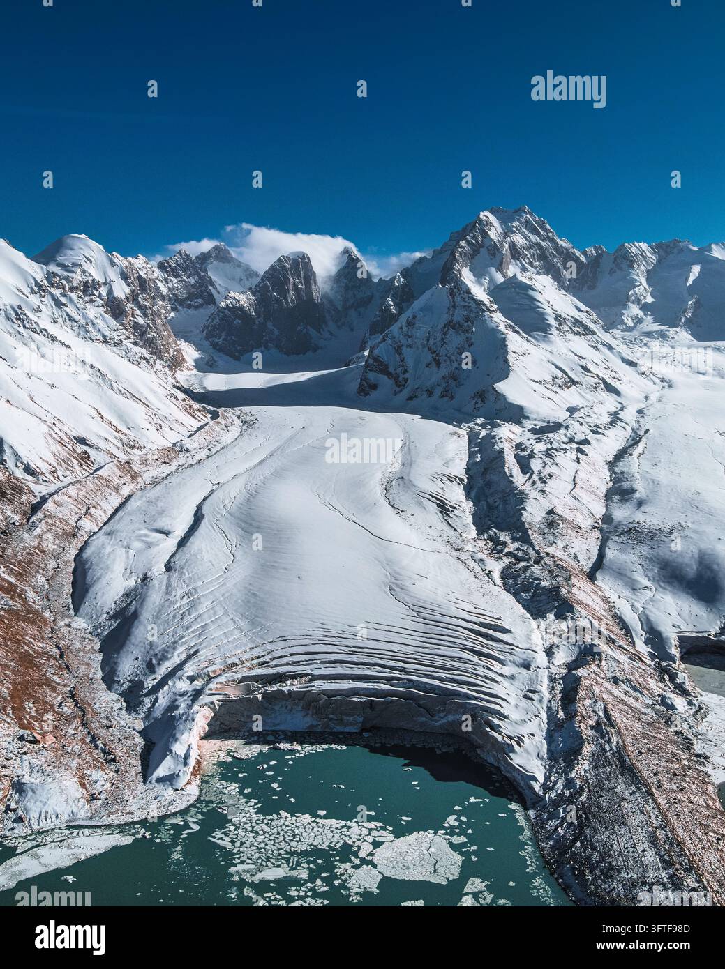 Prospettiva aerea con drone di un vasto flusso di ghiaccio alpino che termina in un lago turchese Foto Stock
