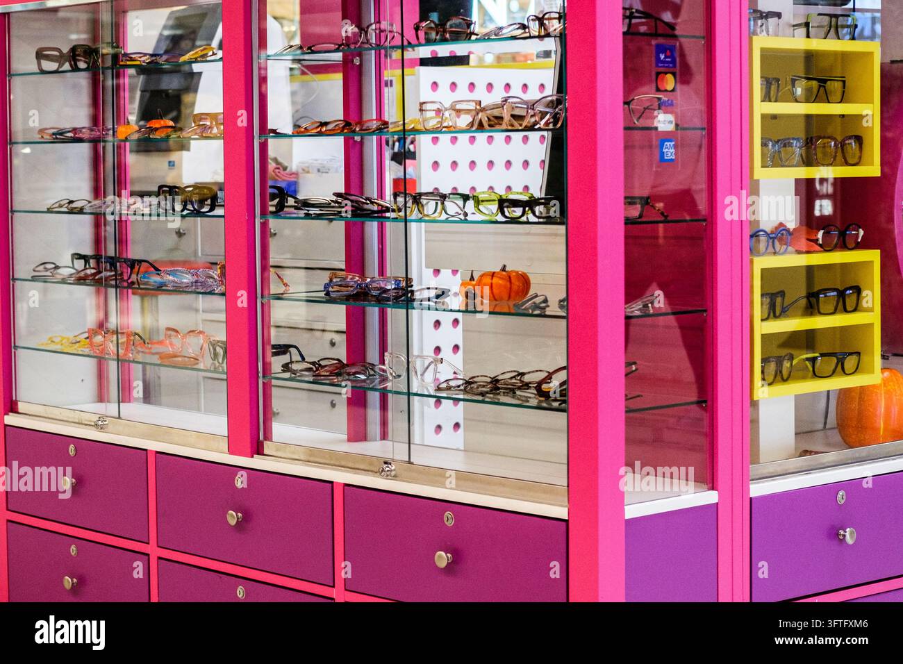 Londra, Regno Unito, 15 ottobre 2026, Occhiali e montature alla moda esposti su scaffali di vetro all'interno di un armadietto ottico rosa e colorato Foto Stock