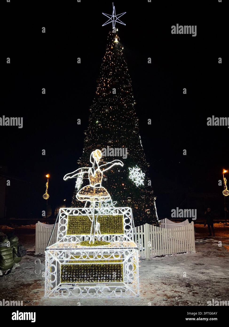 Albero di Natale e installazione luminosa di una scatola musicale con ballerina a Birštonas, Lituania, circondata da una piazza cittadina innevata. Foto Stock