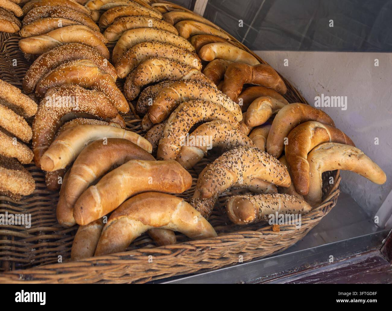 Panini cotti impilati in un cesto di rattan all'interno di una panetteria locale Foto Stock