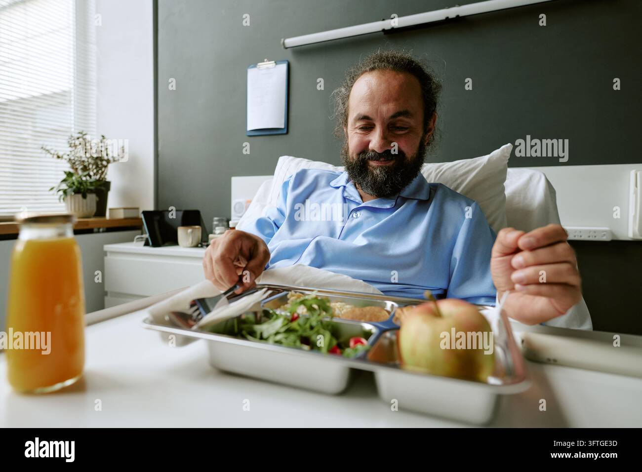 Paziente di mezza età che mangia un pasto sano nel letto d'ospedale Foto Stock