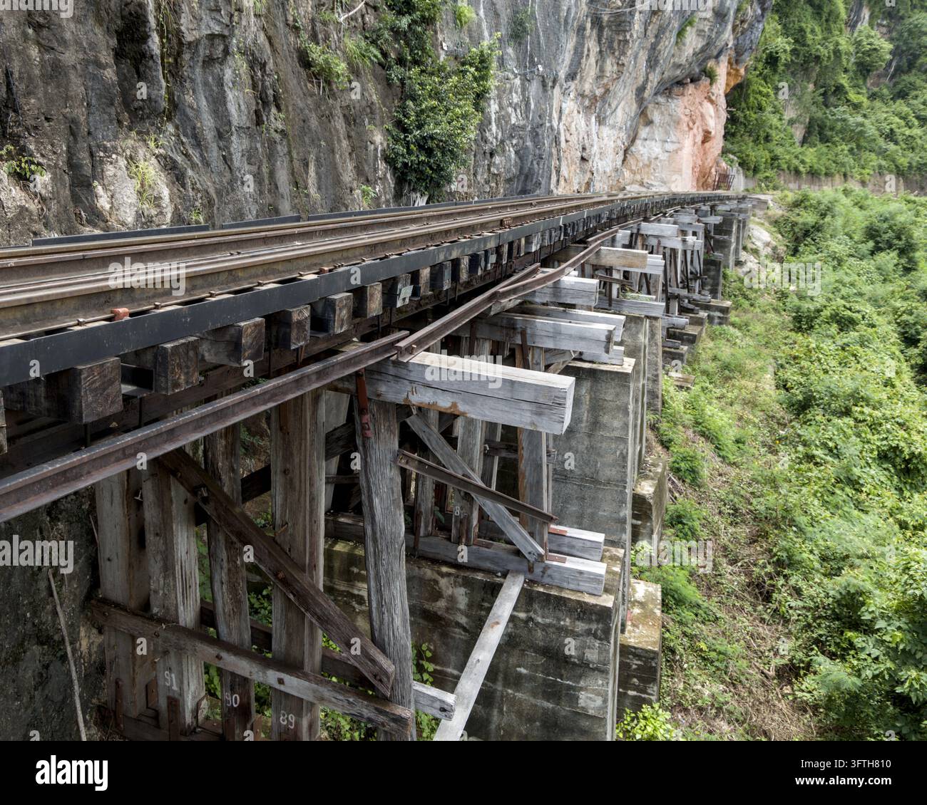 Viadotto ferroviario storico a cavalletti in legno costruito lungo la parete rocciosa di Tham Krasae Kanchanaburi Thailandia Foto Stock