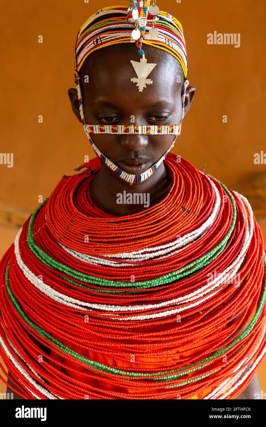 Primo piano di una donna della tribù Samburu che guarda verso il basso con una fascia per il viso decorata con perline e un enorme collare di perline rosse e verdi, Samburu County, Samburu, Kenya Foto Stock