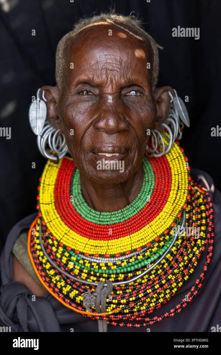 Donna anziana della tribù Turkana con orecchini di foglia d'argento e spessi strati di perle rosse, gialle e verdi, Contea di Marsabit, Loiyangalani, Kenya Foto Stock