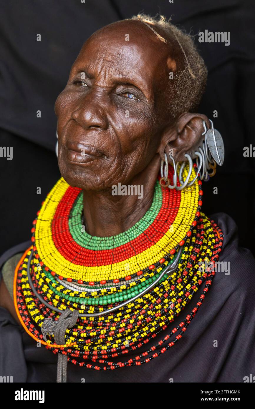 Donna anziana della tribù Turkana che guarda di lato con orecchini a foglia d'argento e strati di collane di perline, Contea di Marsabit, Loiyangalani, Kenya Foto Stock