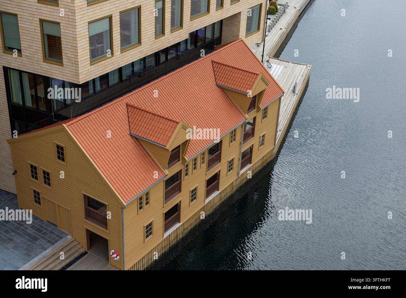 Edificio tradizionale in legno giallo con un tetto di tegole rosse accanto a un canale Foto Stock
