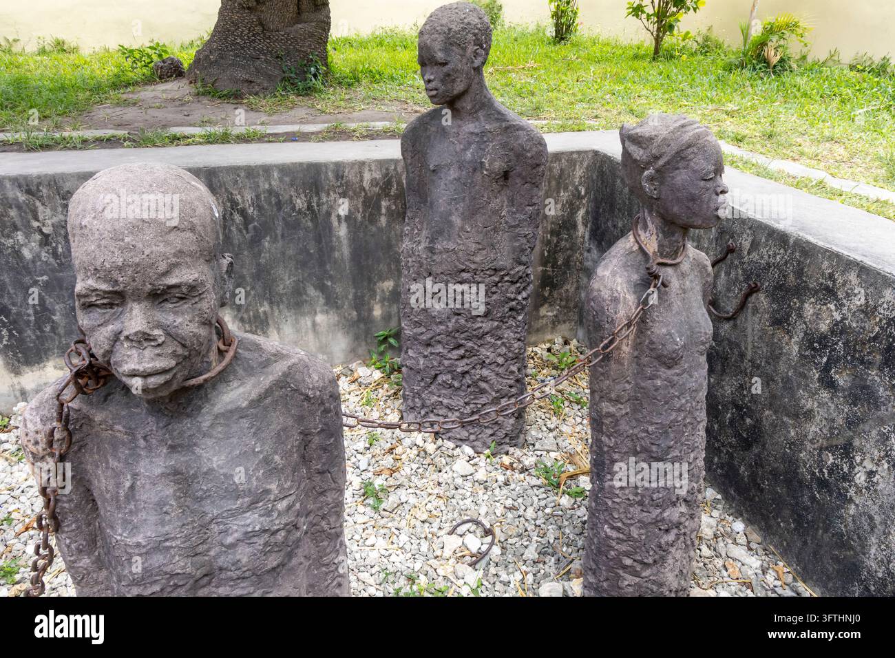 Memoriale della mostra sul commercio di schiavi dell'Africa orientale con prigionieri incatenati scolpiti in una fossa di ghiaia vista dall'alto, Stone Town, Tanzania Foto Stock