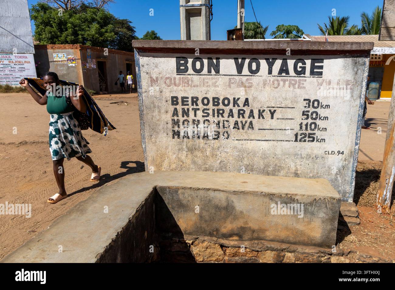Donna che passa davanti a un cartello dipinto con su scritto Bon Voyage, Menabe, Morondava, Madagascar Foto Stock