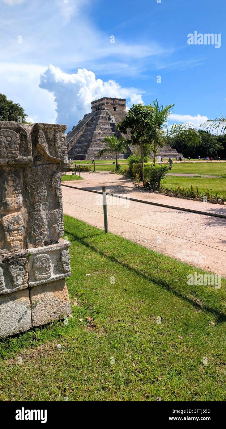 Antica piramide Maya El Castillo a Chichen Itza, Messico, circondata da rovine di pietra storiche e vegetazione tropicale sotto un bellissimo cielo blu Foto Stock