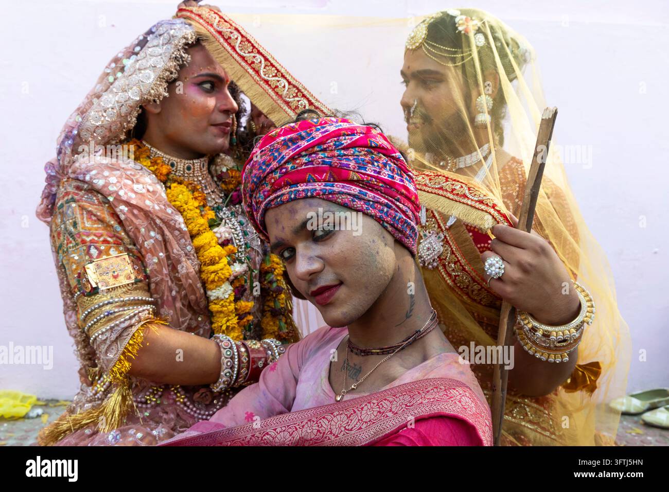 Tre uomini gay vestiti per Holi con veli di paillettes, gonne dorate e un turbante magenta che posano stretti insieme, Uttar Pradesh, Vrindavan, India Foto Stock