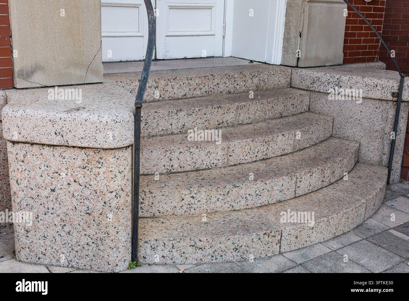 Primo piano di gradini d'ingresso in pietra curvi con ringhiere metalliche che conducono alle doppie porte in legno bianco di un edificio storico in mattoni a Galveston, Texas, USA Foto Stock