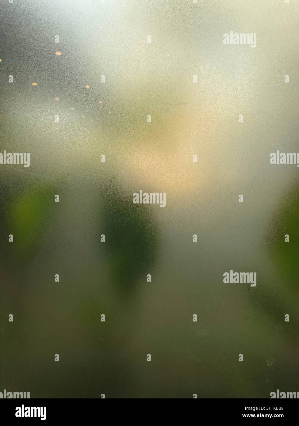 Vetro texturizzato ghiacciato con una silhouette umana morbida e una luce calda sfocata dietro la superficie traslucida Foto Stock