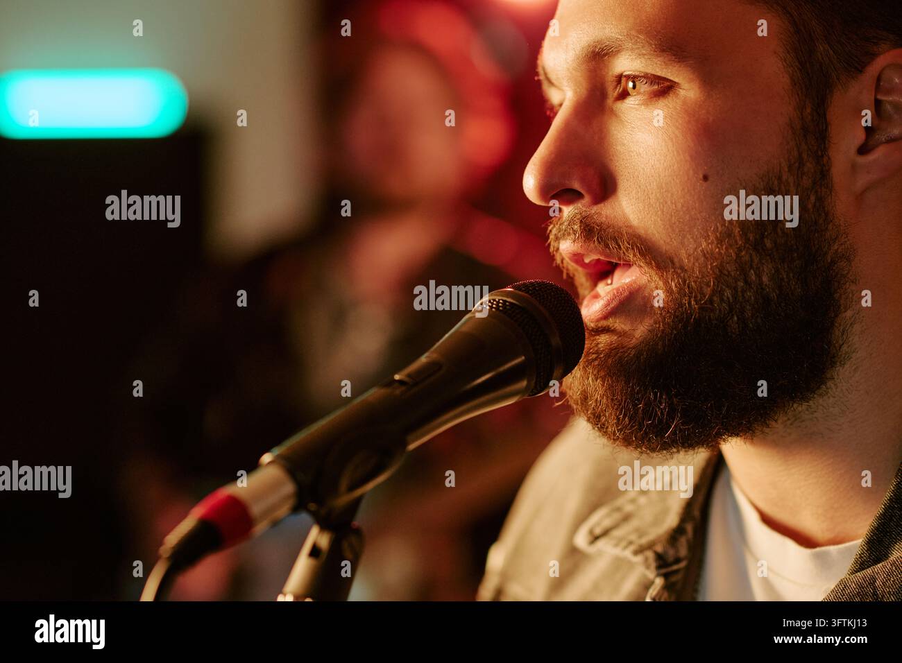 Uomo barbuto che canta in un microfono durante una performance dal vivo in concerto Foto Stock