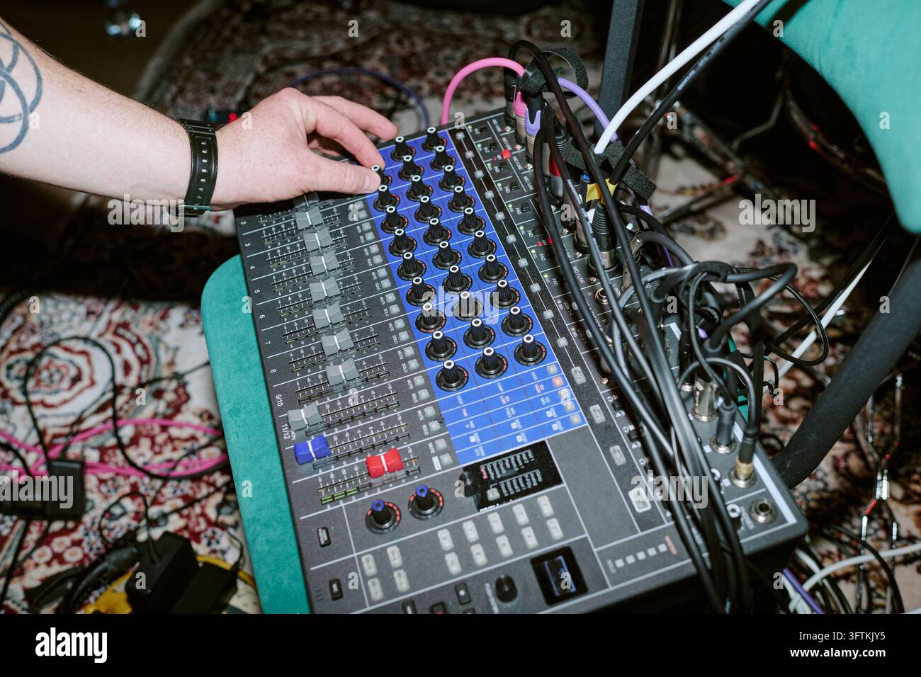 Mano tagliata di un uomo che regola un mixer audio durante una prova dal vivo Foto Stock