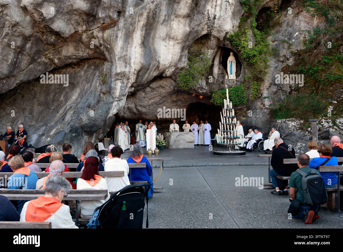 I sacerdoti celebrano una messa cattolica davanti alla Grotte di Massabielle, con numerosi pellegrini seduti tranquillamente sulle panchine del santuario. Lourdes, Fr Foto Stock