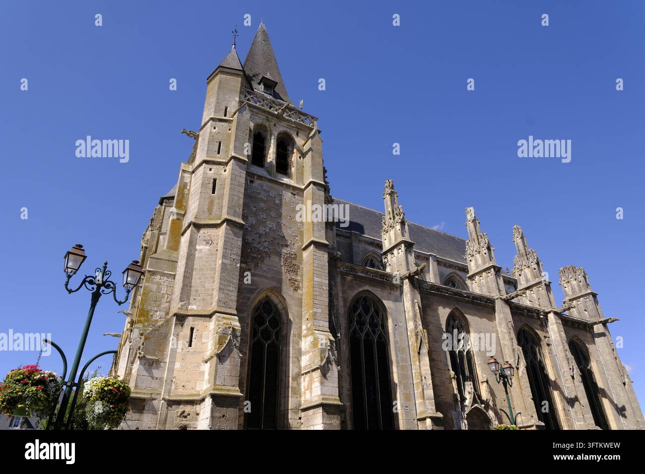 La facciata in pietra della chiesa di Saint-Paul a Neubourg, nel dipartimento dell'Eure in Francia, con il suo campanile, i contrafforti e un lampione adornato Foto Stock