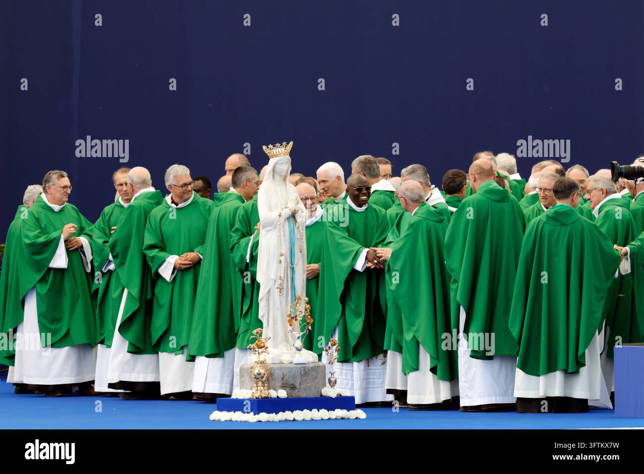 Sacerdoti in casule verdi si scambiano il segno della pace durante una messa all'aperto celebrata da Papa Leone XIV. Lourdes, Francia. Foto Stock