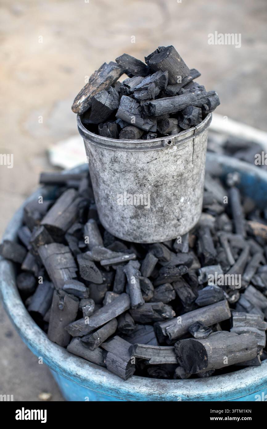 In Ruanda, pezzi di carbone usati per cucinare riempiono un contenitore di plastica logoro. Foto Stock