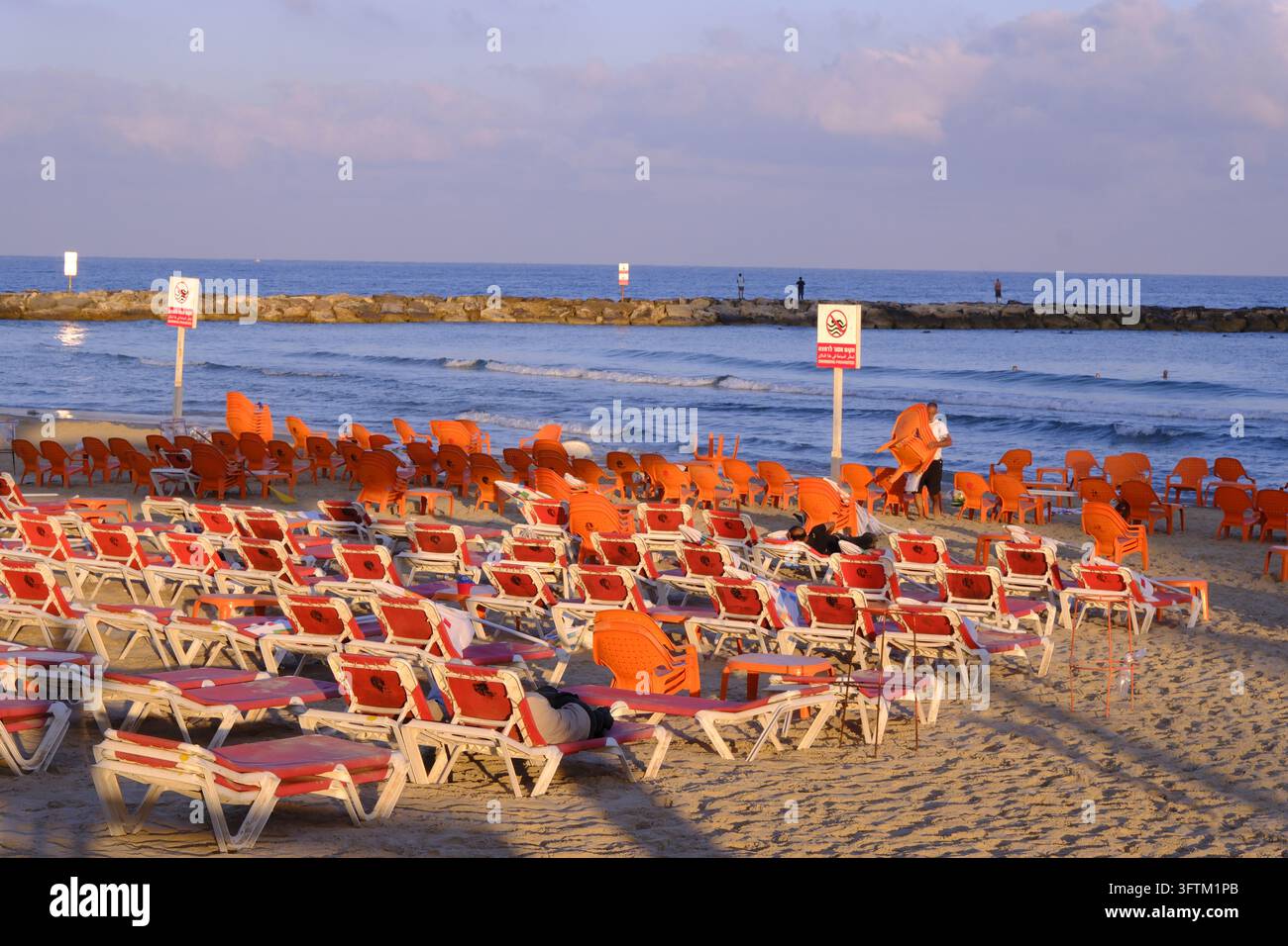 Molte sedie da spiaggia rosse costeggiano la riva sabbiosa rivolta verso il mare a Tel Aviv, Israele. Foto Stock