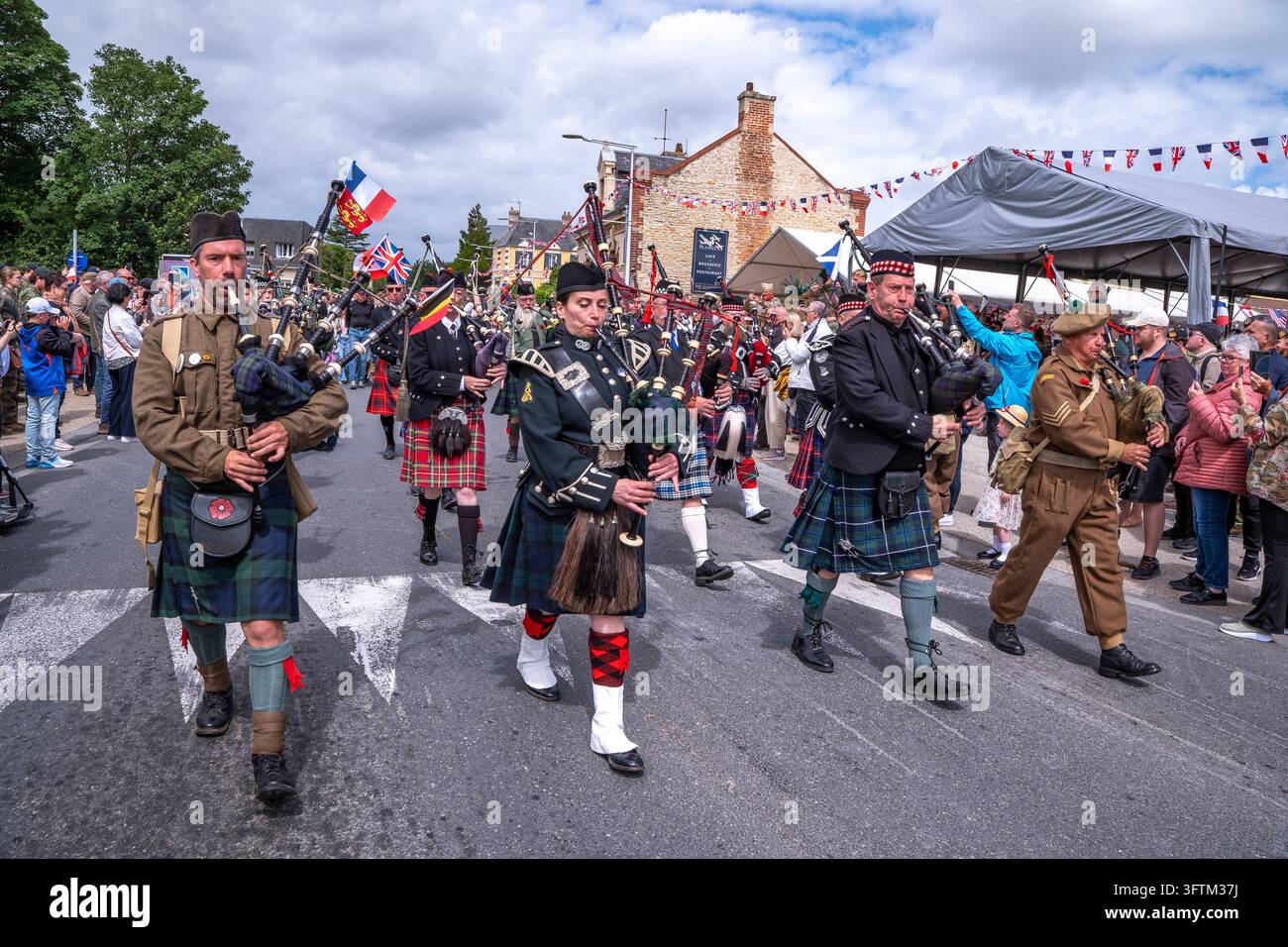 I suonatori di cornamuse in kilt sfilano durante una commemorazione dello sbarco militare a Bénouville, Calvados. Foto Stock