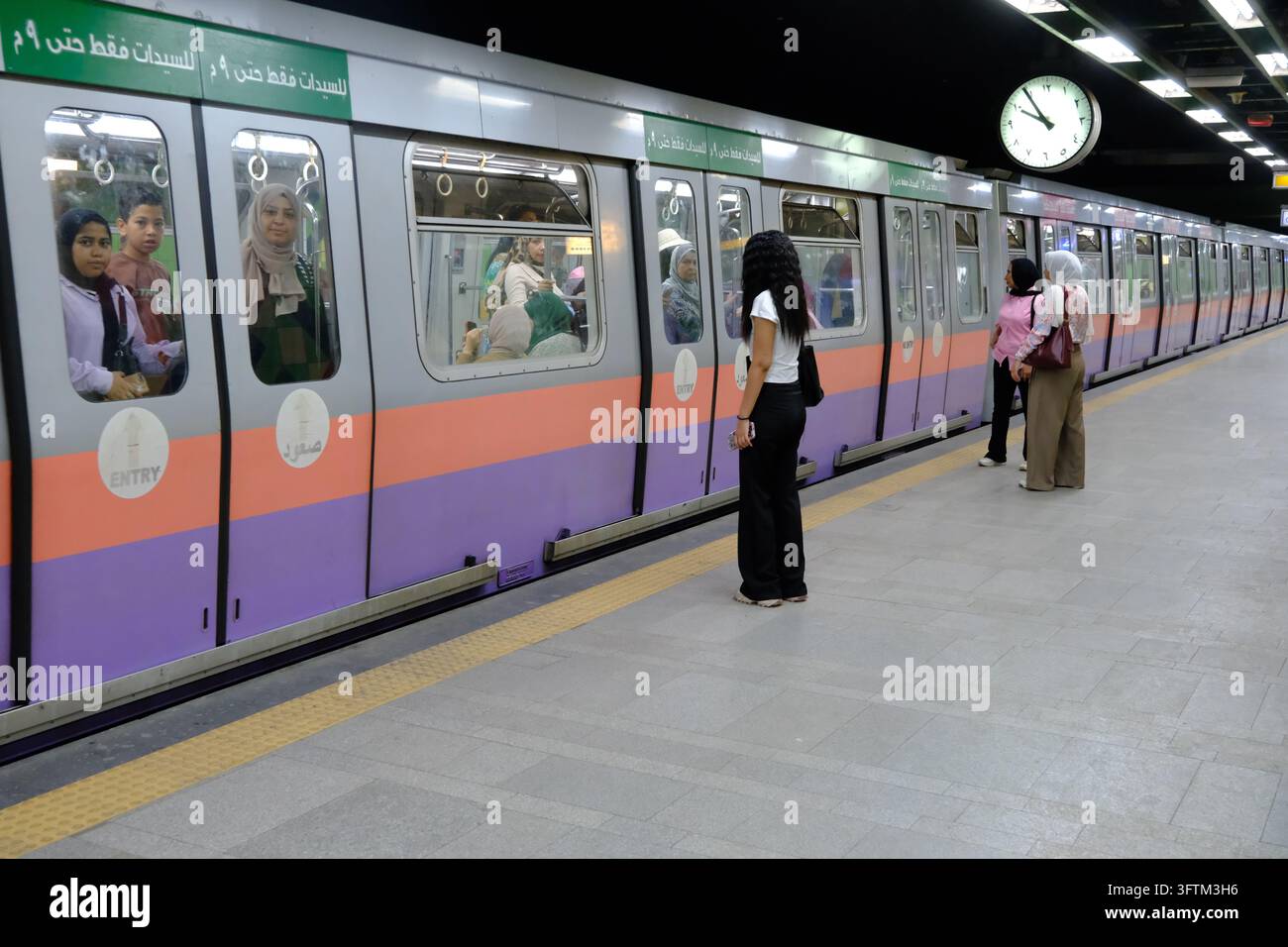 Passeggere attendono sul binario davanti a un treno della metropolitana riservato alle donne al Cairo, in Egitto. Foto Stock