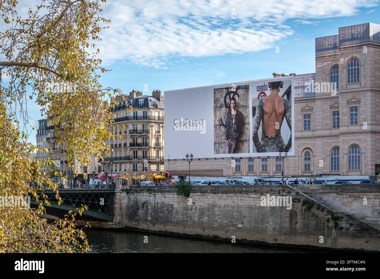 Grande cartellone pubblicitario Saint Laurent sopra gli impalcati dei lavori di restauro sulla facciata di un edificio parigino accanto alla Senna Foto Stock
