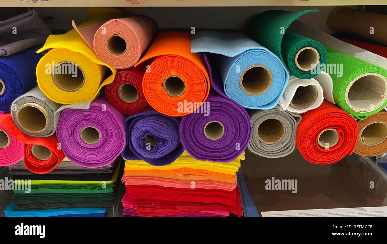 Rotoli di tessuto di feltro colorati assortiti nei colori dell'arcobaleno esposti su scaffali in un negozio di articoli per il fai-da-te Foto Stock