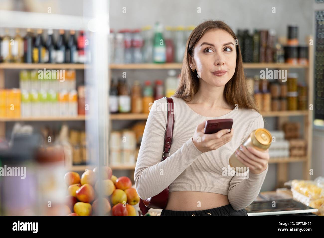 L'acquirente donna esegue la scansione del codice QR sull'etichetta della birra nel negozio di alimentari Foto Stock