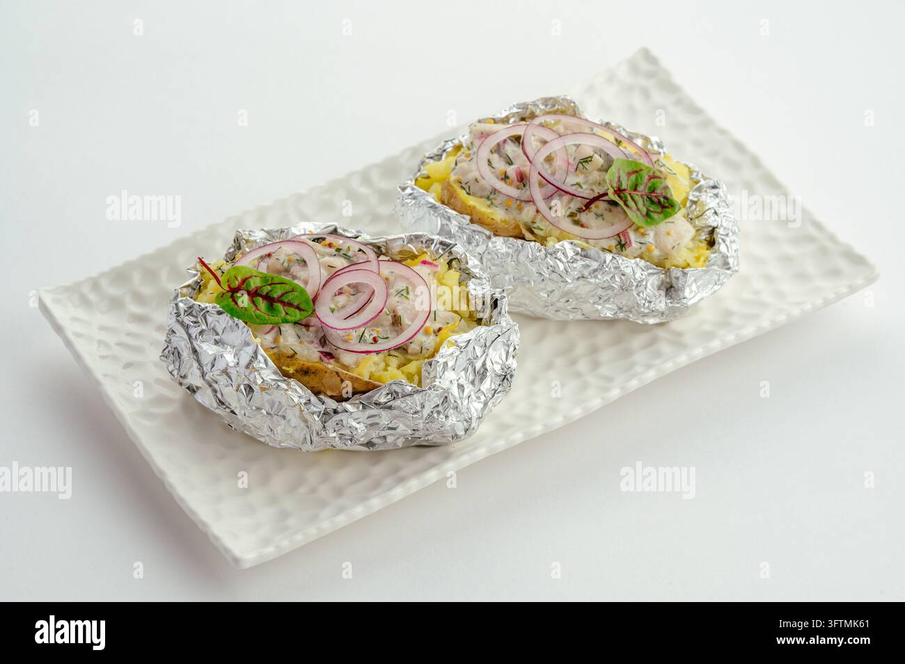 Due patate al forno cariche con cipolla rossa ed erbe Foto Stock