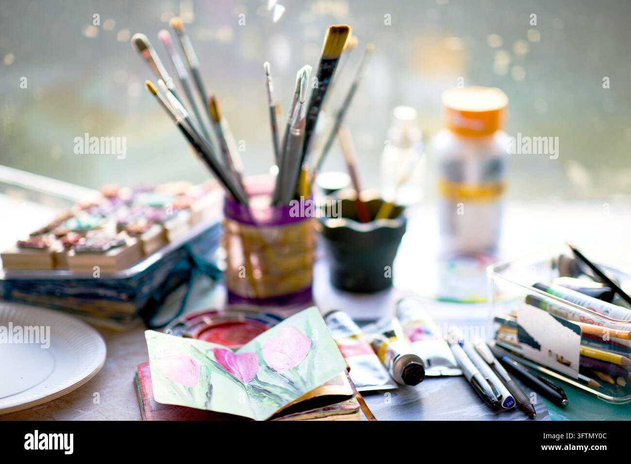 Spazio di lavoro creativo per il journaling artistico con carte colorate, pennelli, colori e materiali artistici misti su un tavolo, che ispira la creatività artistica Foto Stock