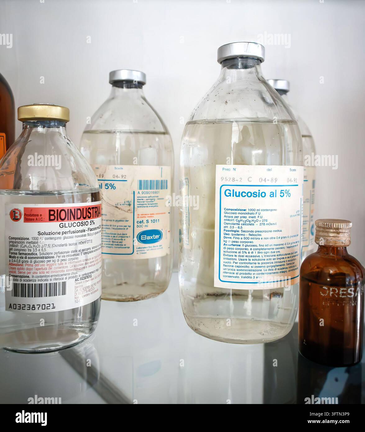 Bottiglie di soluzione chiara contenenti Glucosio al 5 percento di Bioindustria e Baxter su uno scaffale Foto Stock