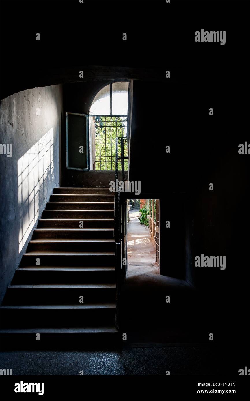 Ombre leggere e drammatiche su una scala interna del carcere con ringhiere all'interno dell'edificio Foto Stock