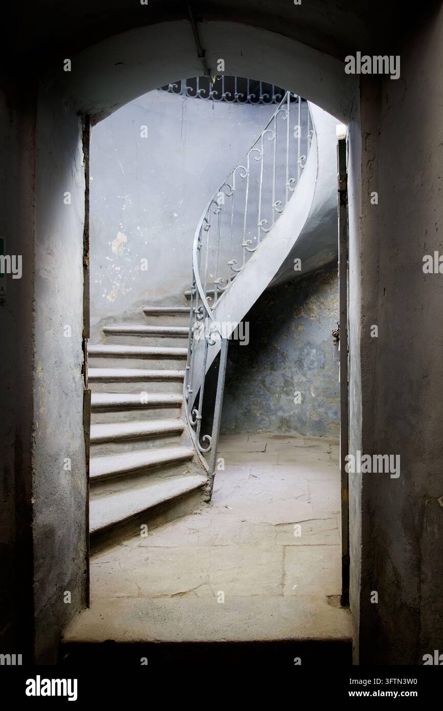 Scalinata a chiocciola con ringhiera bianca vista attraverso un ingresso ad arco nell'interno di un edificio Foto Stock