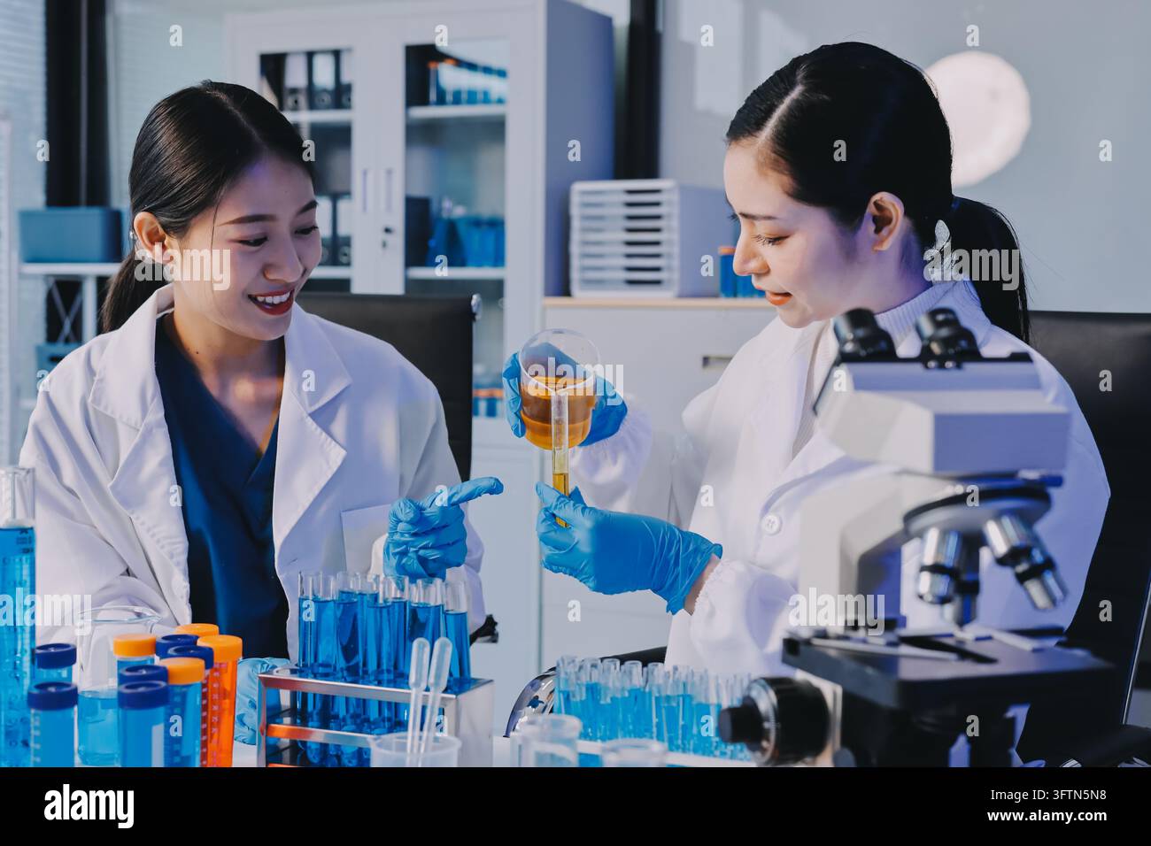 Un ricercatore medico o scientifico o un medico che osservi una provetta di soluzione limpida in un laboratorio Foto Stock