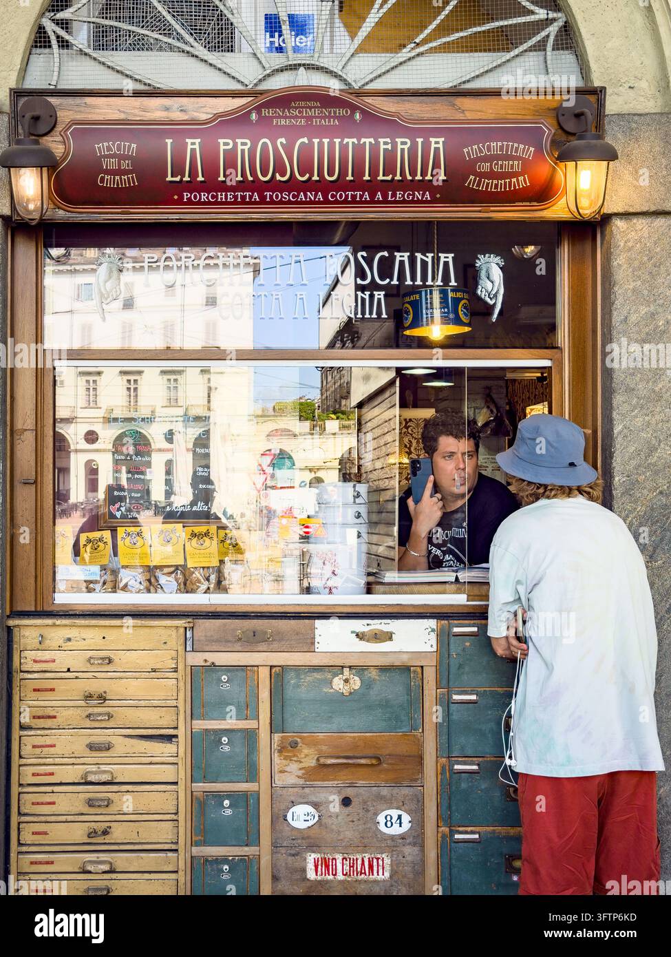 Cliente alla finestra del negozio La Prosciutteria a Torino che vende porchetta e vino La Prosciutteria – Porchetta Toscana Cotta a Legna Foto Stock