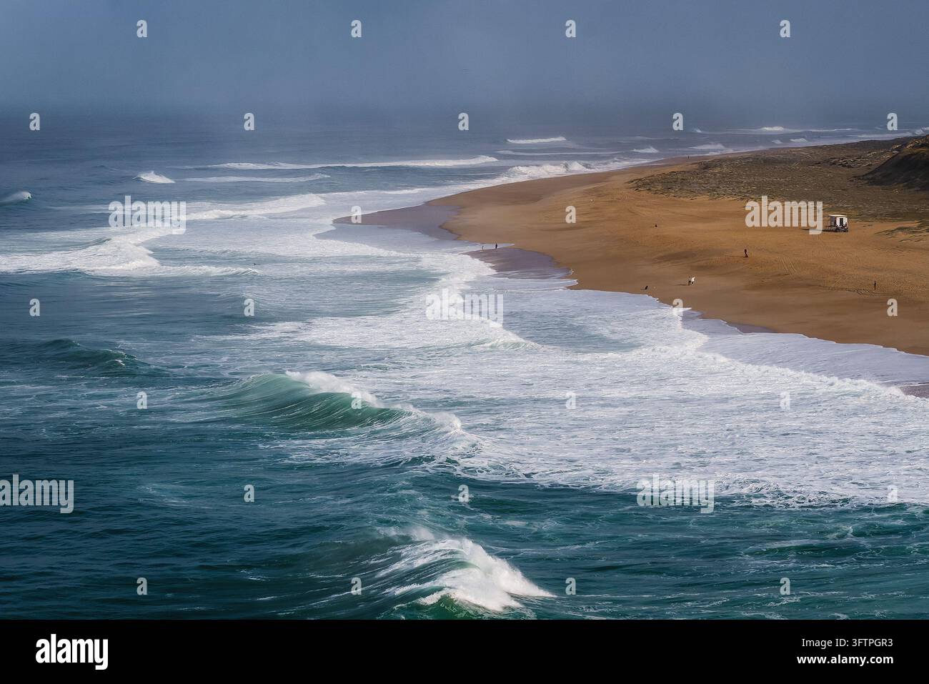 Enorme onda dell'Oceano Atlantico che si arriccia con schiuma bianca a Nazaré, Portogallo Foto Stock