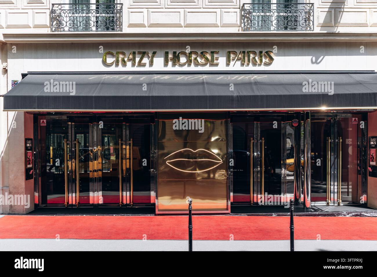 Parigi, Francia – 23 maggio 2026: Ingresso del cabaret Crazy Horse Paris su Avenue George V, con lettere dorate, logo a labbra illuminato, porta in vetro Foto Stock