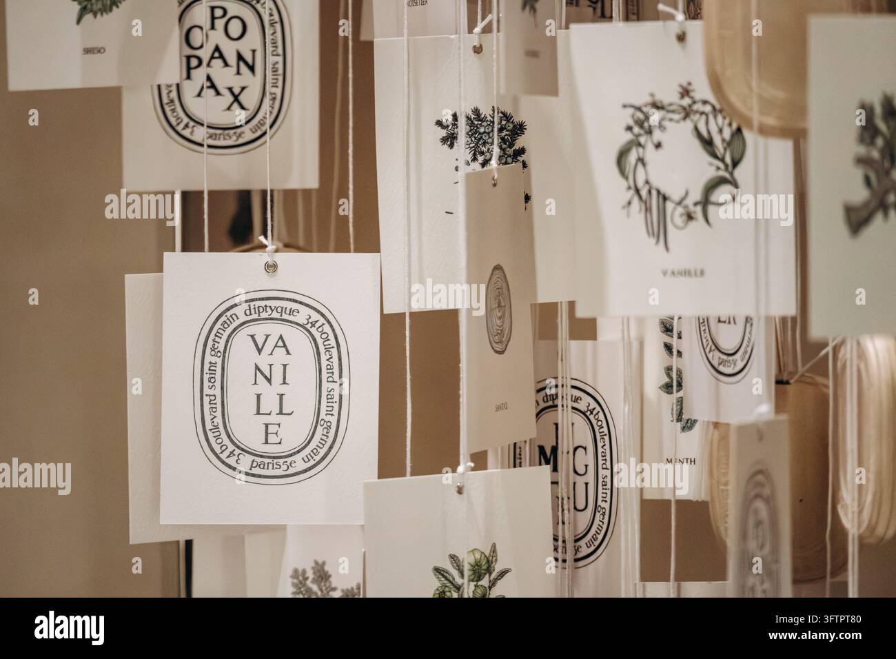 Parigi, Francia - 24 maggio 2026: Biglietti profumati Diptyque appesi con illustrazioni botaniche e nomi di profumi formano una mostra decorativa all'interno di una boutique Foto Stock