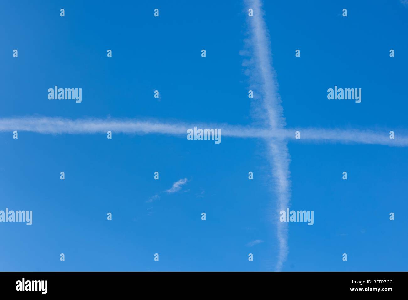 Tracciamenti di jet incrociati che formano una croce bianca su un cielo blu terso Foto Stock