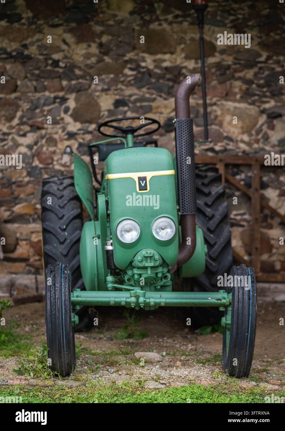 Trattore verde vintage con fari rotondi esposto davanti a un muro di pietra al Maniero di Pakruojis, in Lituania. Foto Stock