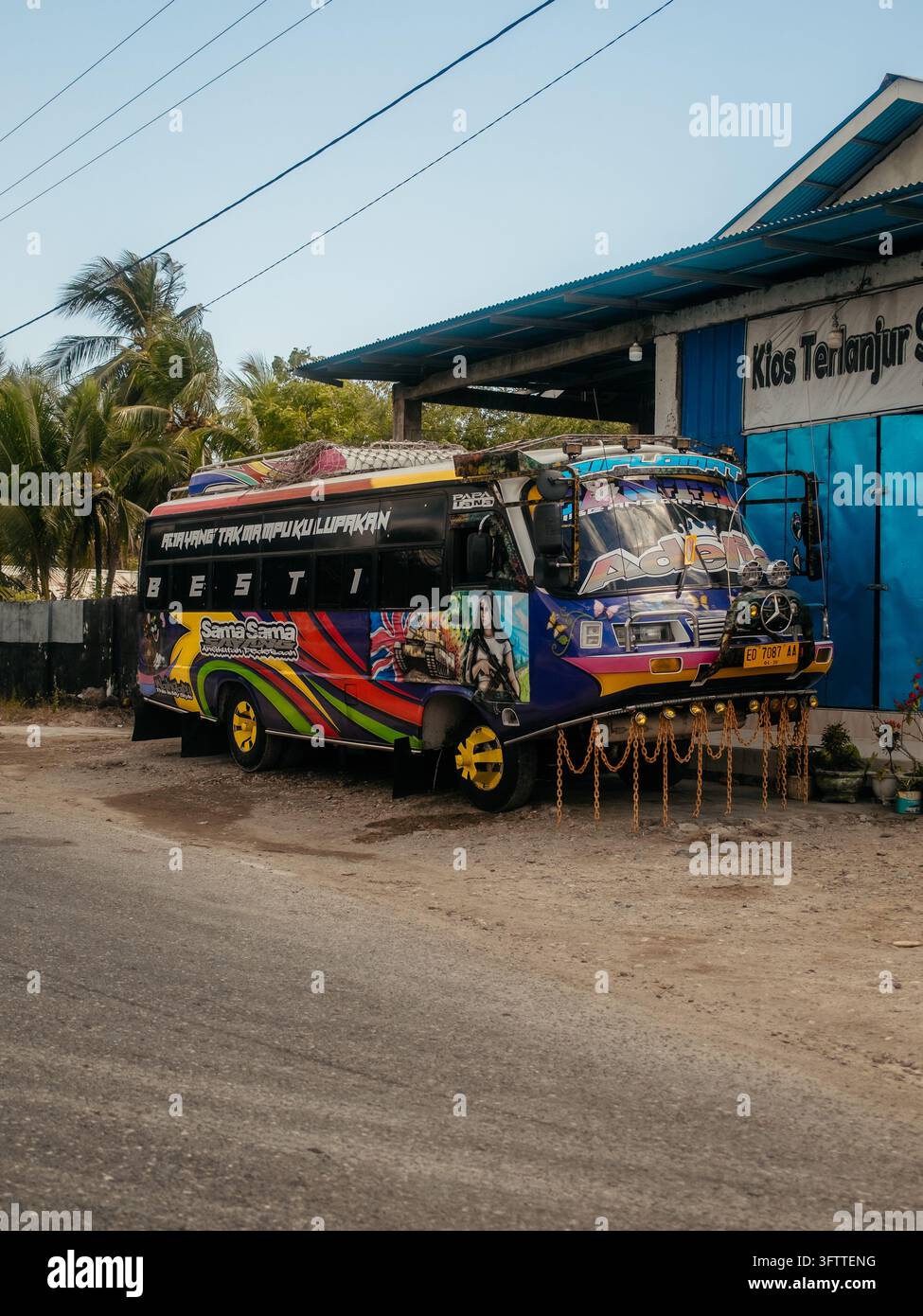 Waikabubak, Indonesia - 03 agosto 2026: Vista di un minibus colorato e riccamente decorato parcheggiato sul ciglio della strada con una vivace verniciatura personalizzata e C appese Foto Stock