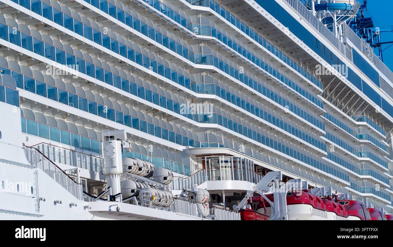Ponti di una nave da crociera visti di lato, file di cabine con balconi e scialuppe di salvataggio nonché attrezzature di coperta nella parte inferiore dell'inquadratura Foto Stock