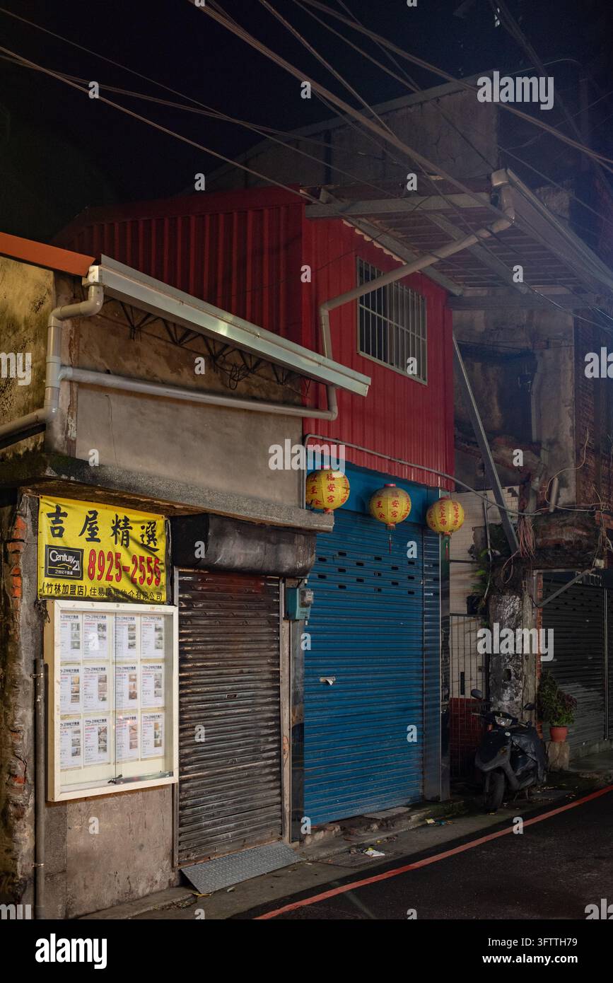 Distretto di Yonghe, Nuova Taipei, Taiwan – 14 giugno 2015: Vista di una vetrina tradizionale a livello della strada con una serranda metallica blu, lanterne di carta gialle Foto Stock