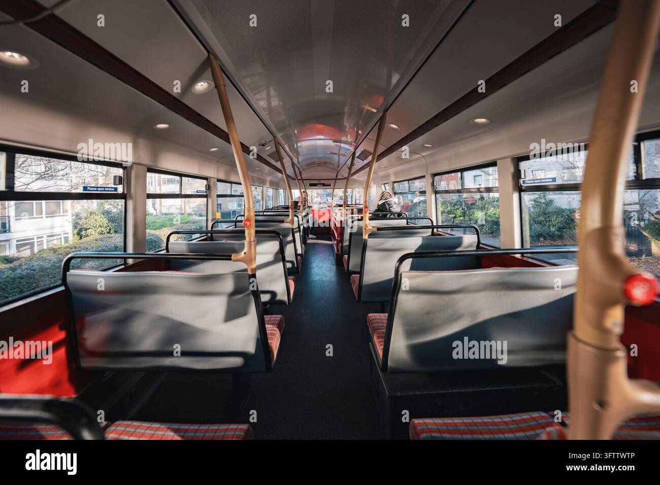 Vista attraverso l'interno di un autobus con file di sedili vuoti e cuscini a scacchi rossi, Londra, Regno Unito Foto Stock