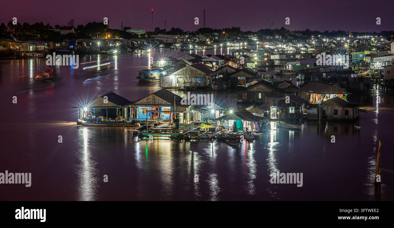 Case galleggianti illuminate e allevamenti ittici di notte sul fiume, Con Tien, Chau Doc, An Giang, Delta del Mekong, Vietnam Foto Stock