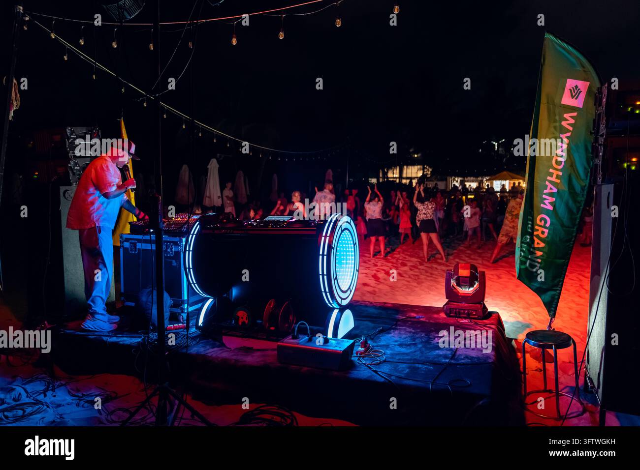 Grand World, Phu Quoc, Vietnam - 12 aprile 2026: Un DJ si esibisce su un palco sulla spiaggia mentre i visitatori ballano e si radunano durante un evento di intrattenimento serale Foto Stock