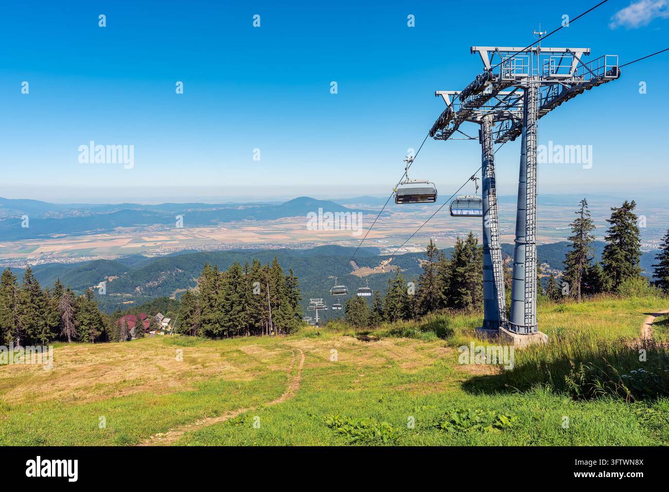 Seggiovante che scende sopra le piste da sci verdi del resort di Poiana Brasov nei Carpazi in Romania Foto Stock