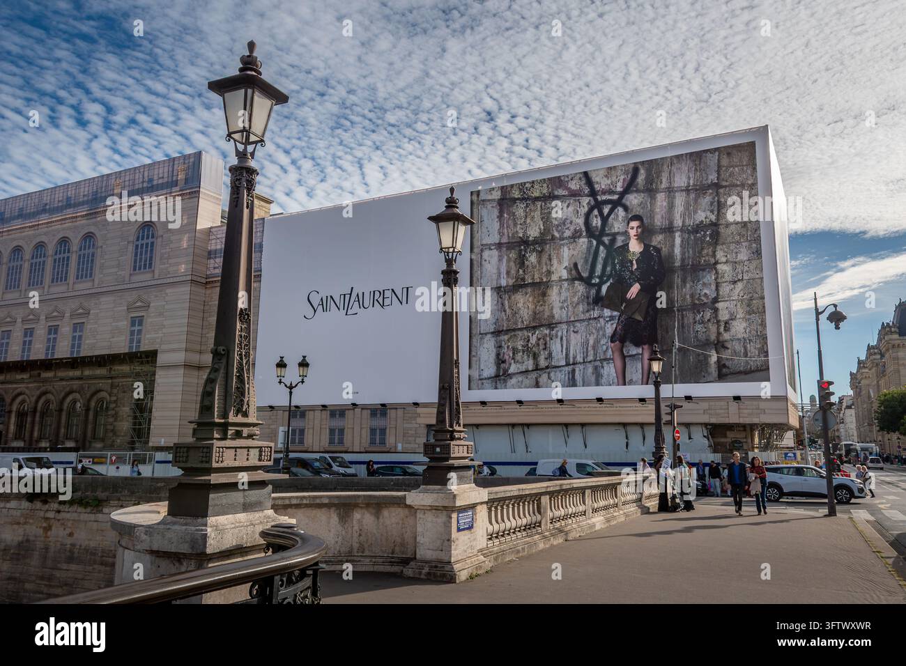 Grande cartellone pubblicitario Saint Laurent sopra gli impalcati dei lavori di restauro sulla facciata di un edificio parigino accanto alla Senna Foto Stock