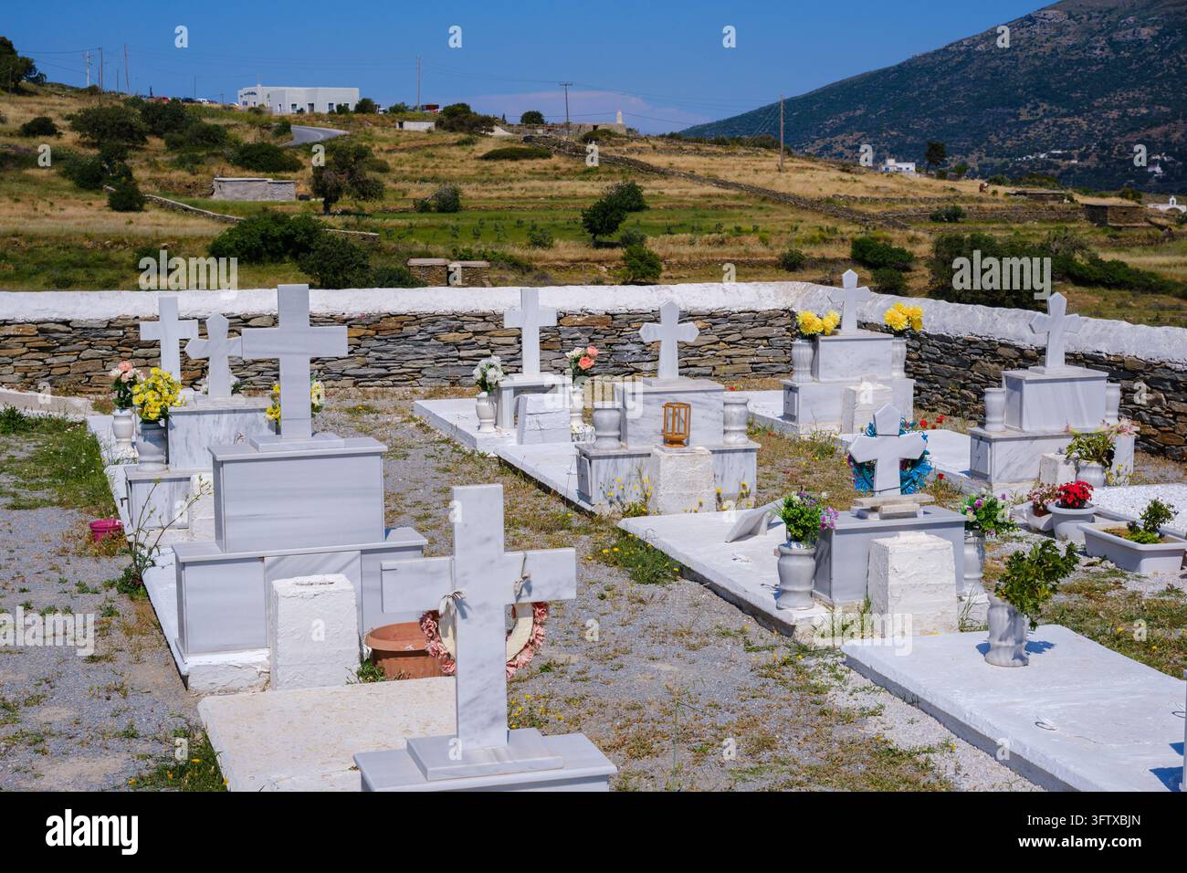 Andros, Grecia - 21 maggio 2026: Cimitero con tombe di marmo bianco e monumenti in pietra su una collina Foto Stock