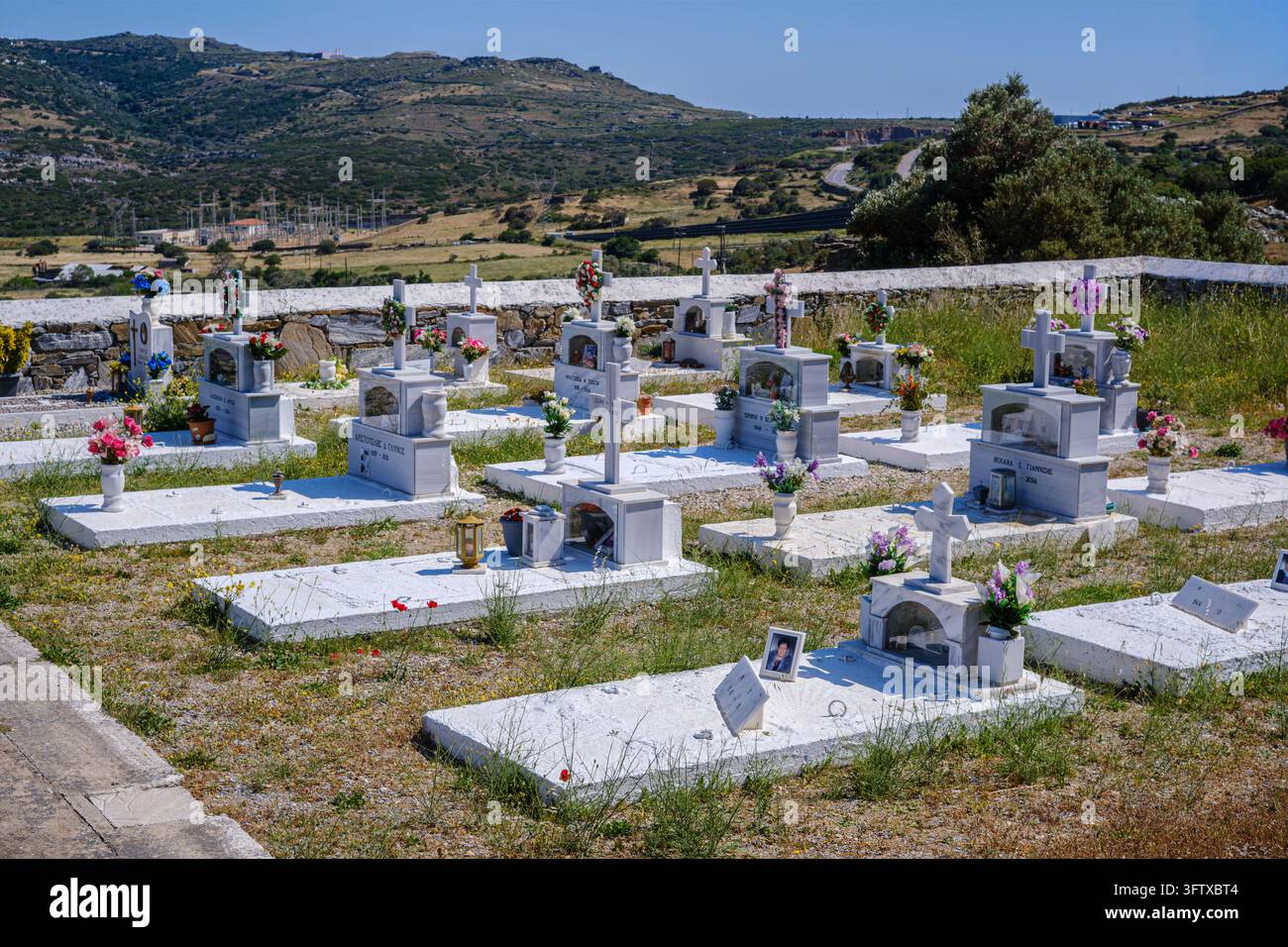 Andros, Grecia - 21 maggio 2026: Cimitero con tombe di marmo bianco e monumenti in pietra su una collina Foto Stock